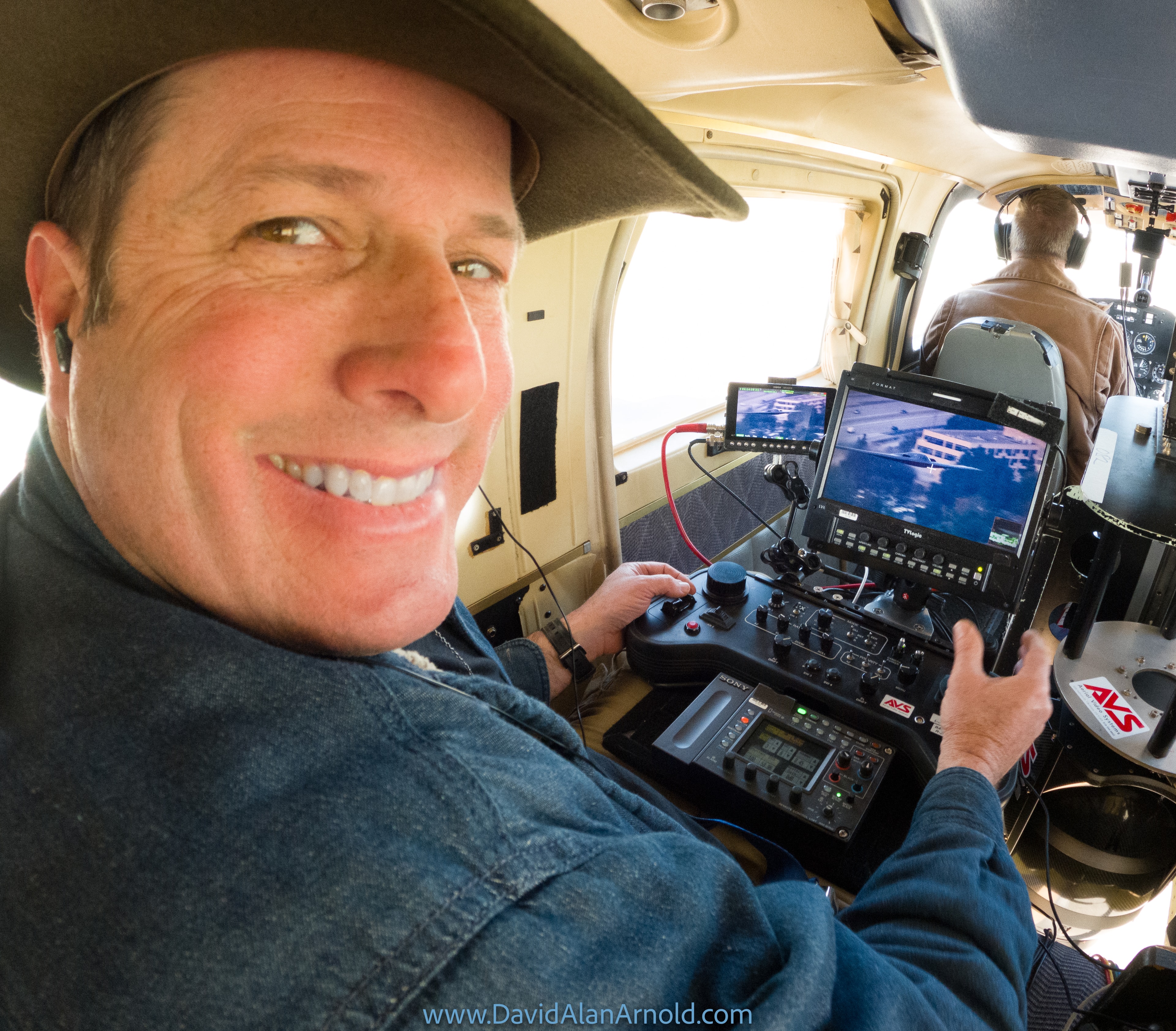 David Alan Arnold at the camera controls inside the helicopter, monitors showing aerial footage