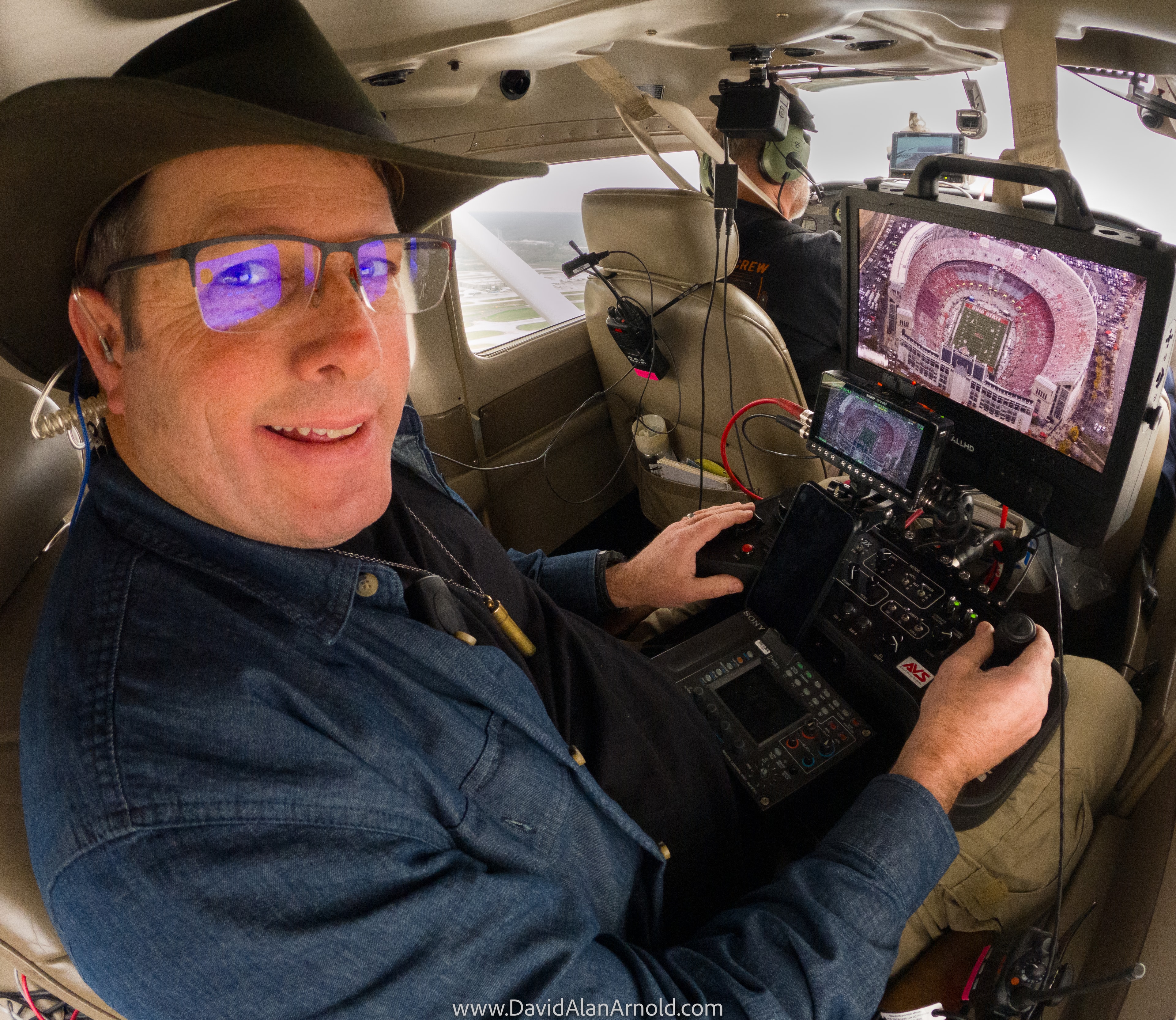David Alan Arnold at the controls with a packed stadium visible on the monitor