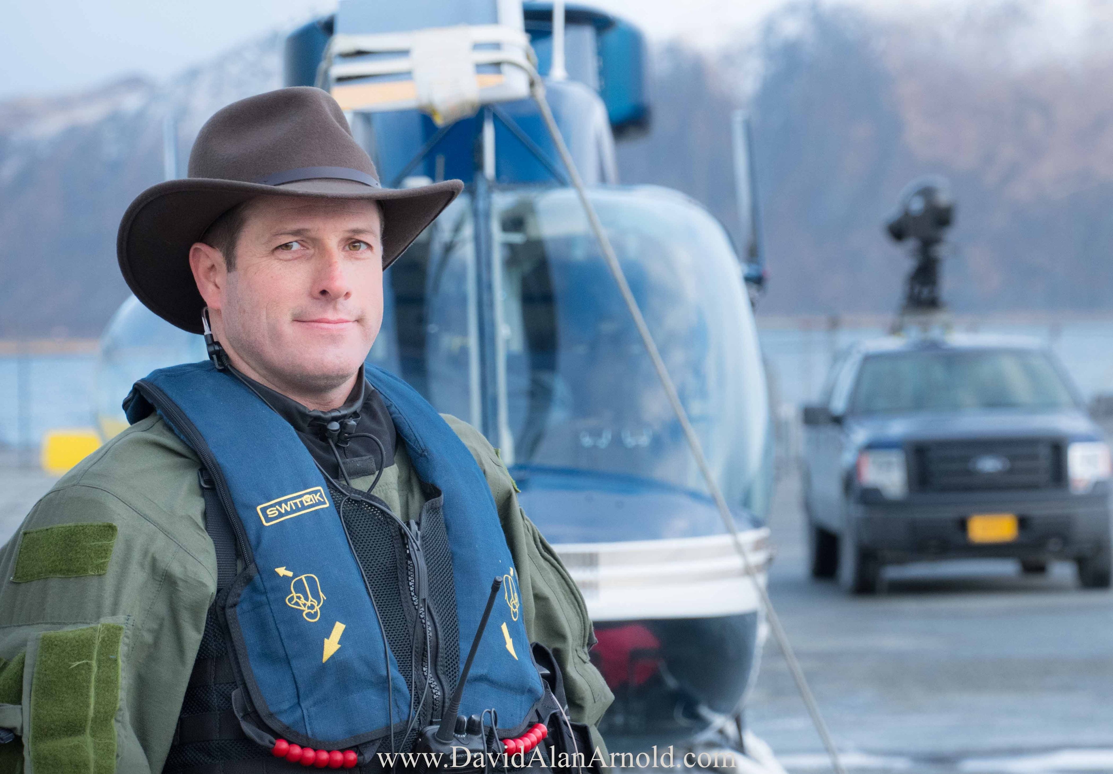 David Alan Arnold in survival gear and cowboy hat with helicopters in the background, Deadliest Catch season 18