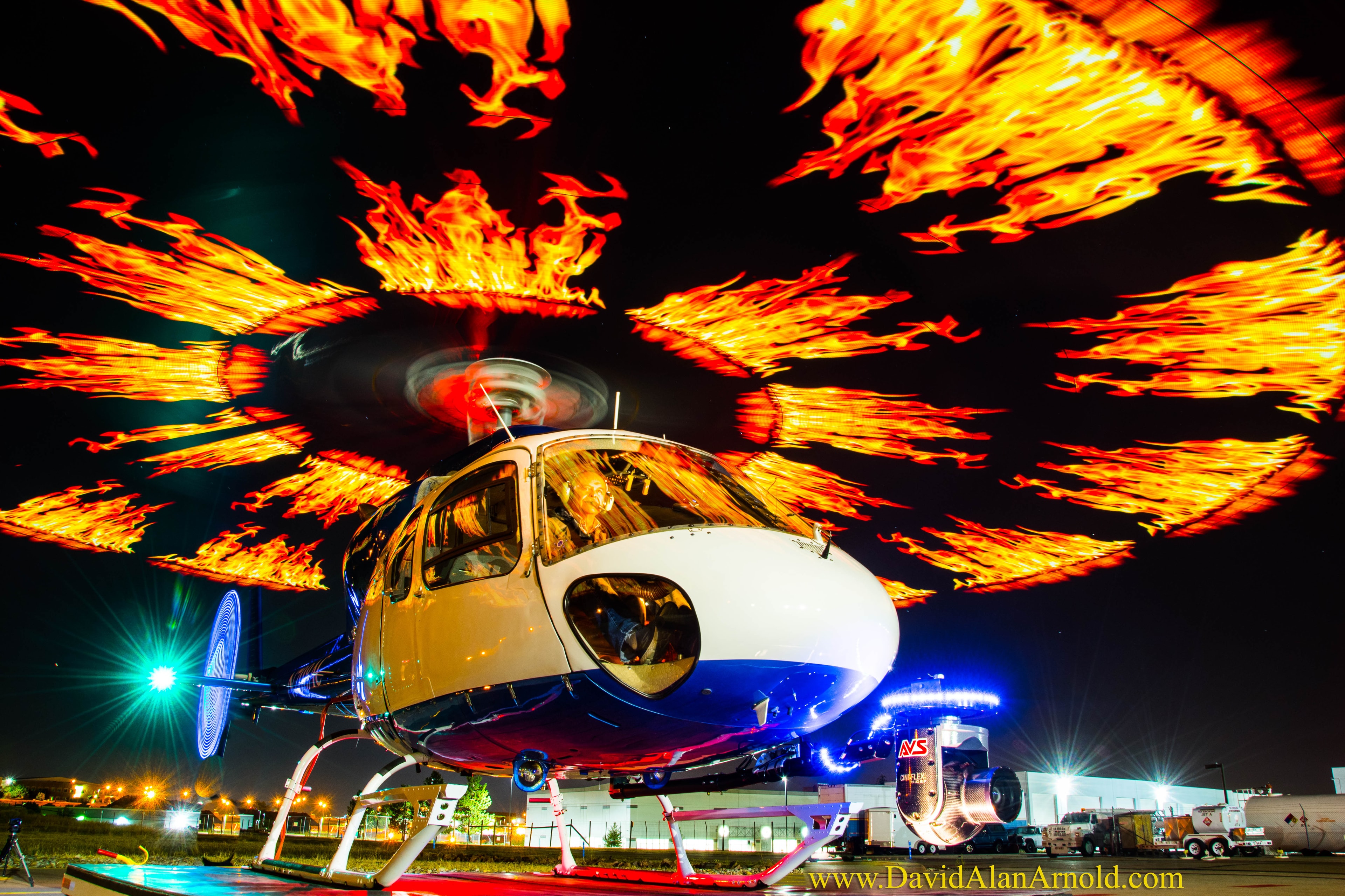 Dramatic long-exposure photograph of helicopter on tarmac at night with fire light painting effect, Monday Night Football Denver