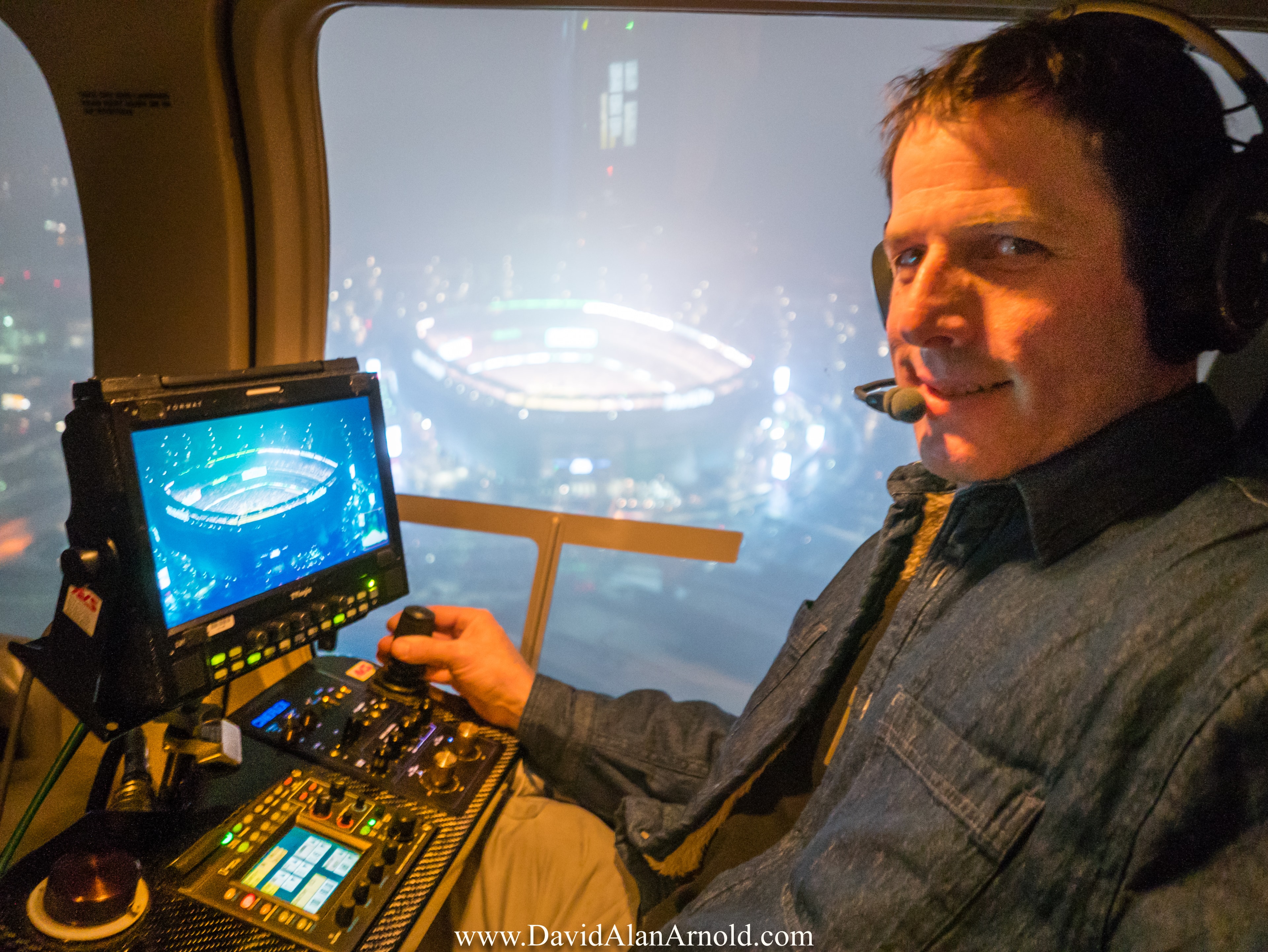 David Alan Arnold operating aerial camera controls at night above a glowing NFL stadium, Monday Night Football New York Giants